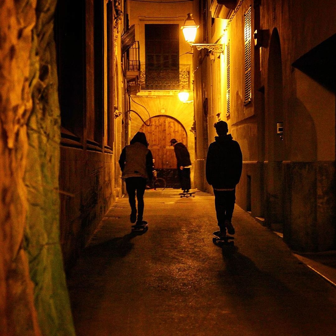 REAR VIEW OF MEN WALKING IN ILLUMINATED CORRIDOR