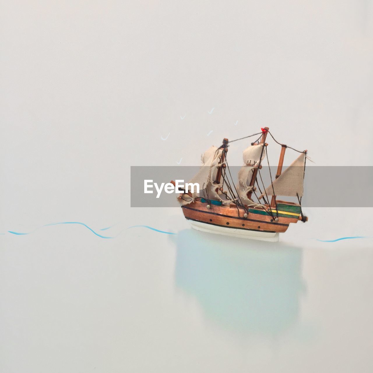 Close-up of toy ship floating on water against white background