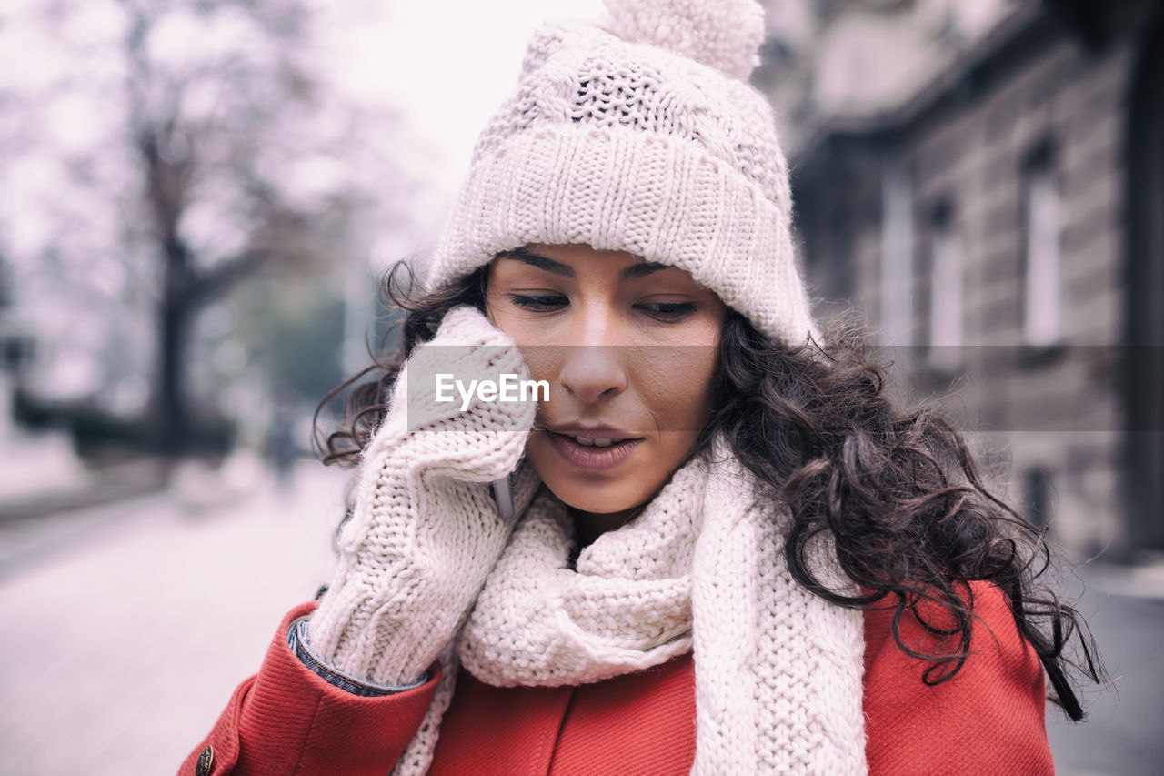 Young woman talking on mobile phone outdoors during winter