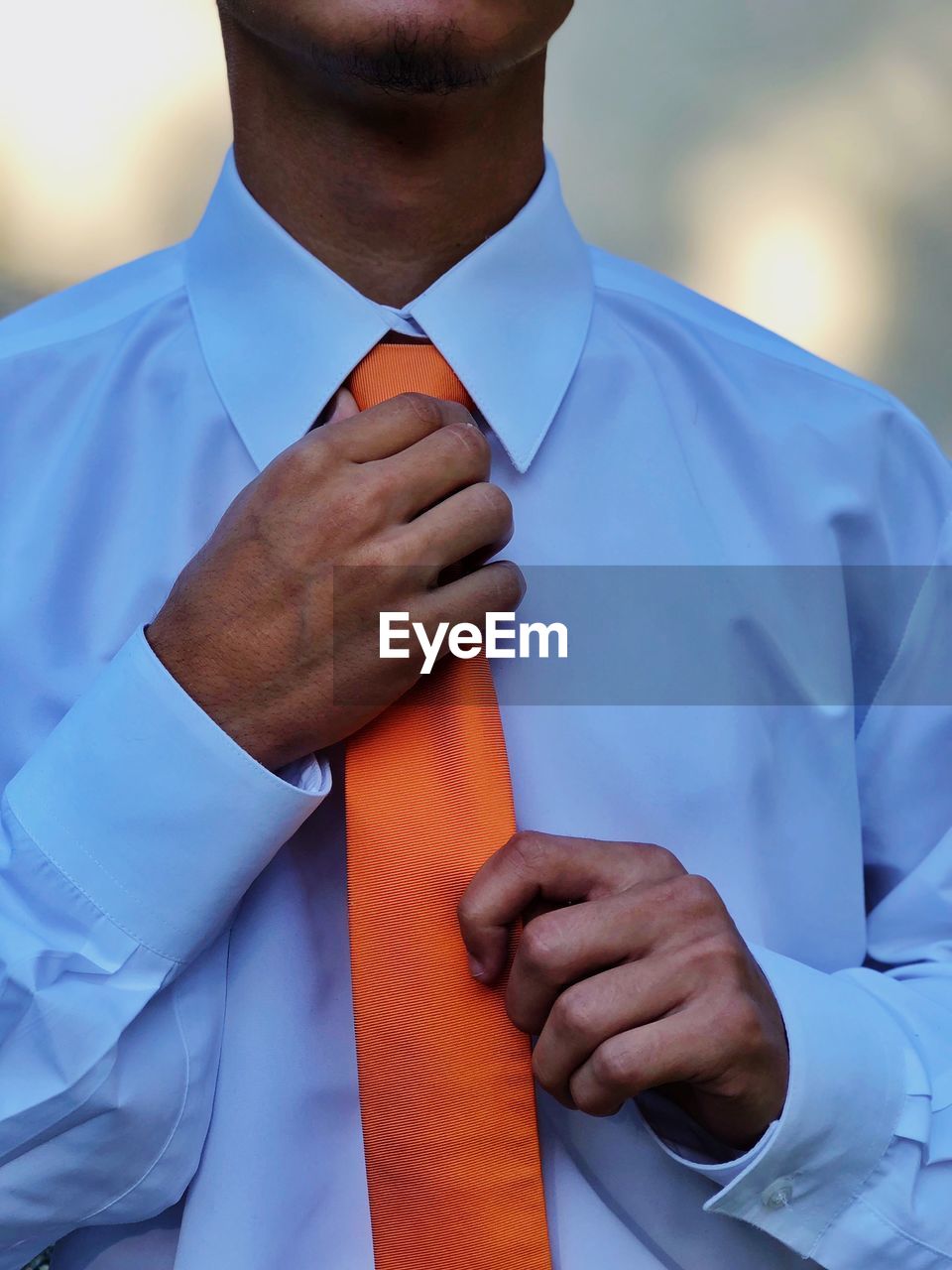 Midsection of man adjusting necktie