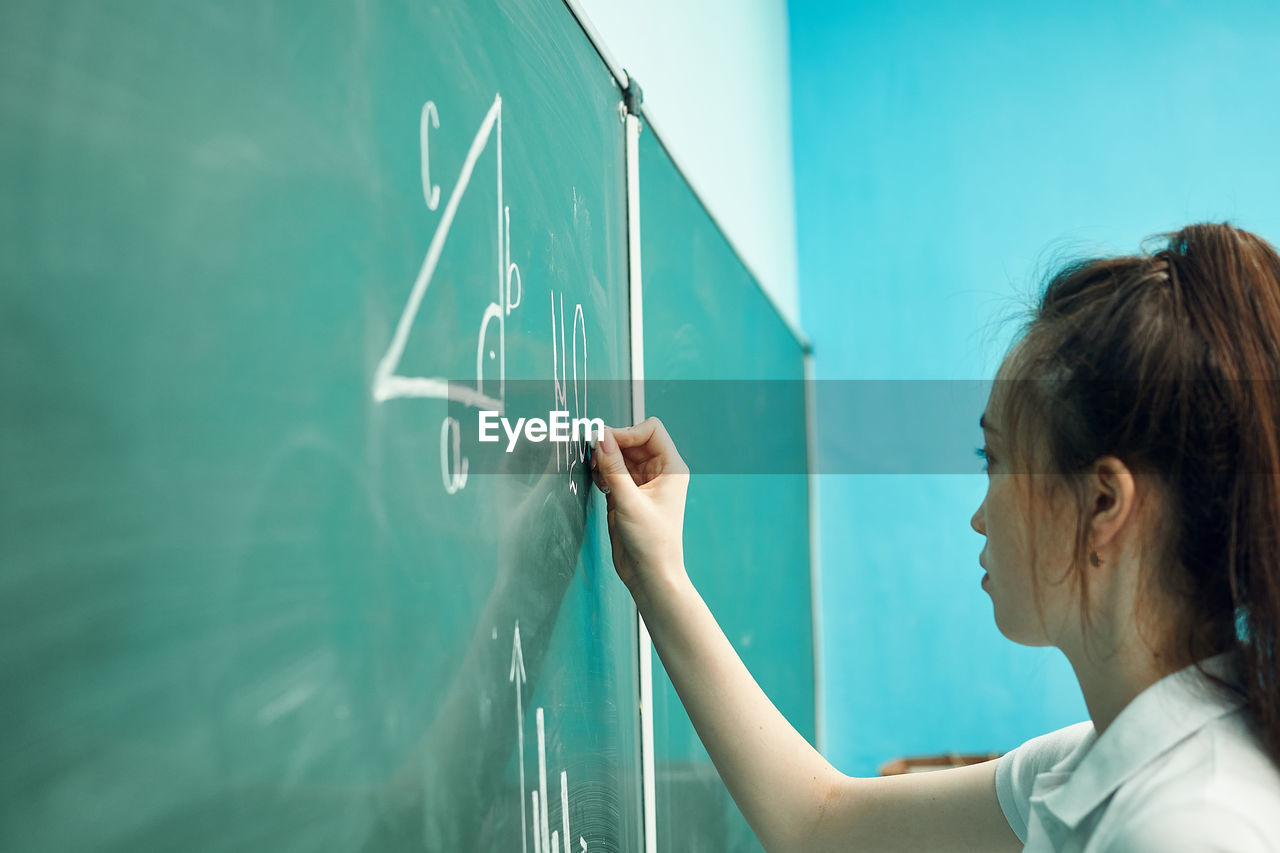 Asian high school girl solves geometry on the blackboard