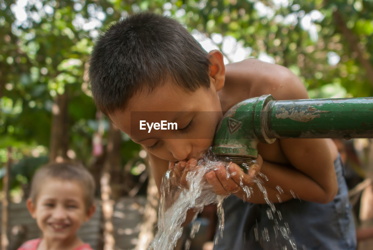 PORTRAIT OF CUTE BOY DRINKING WATER IN PARK