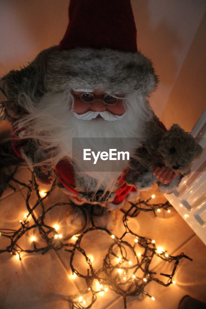 High angle view of santa claus with christmas lights on table at home