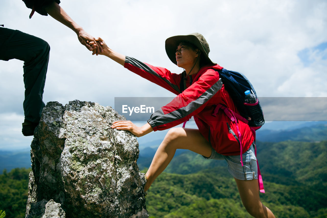 low angle view of young man climbing on rock