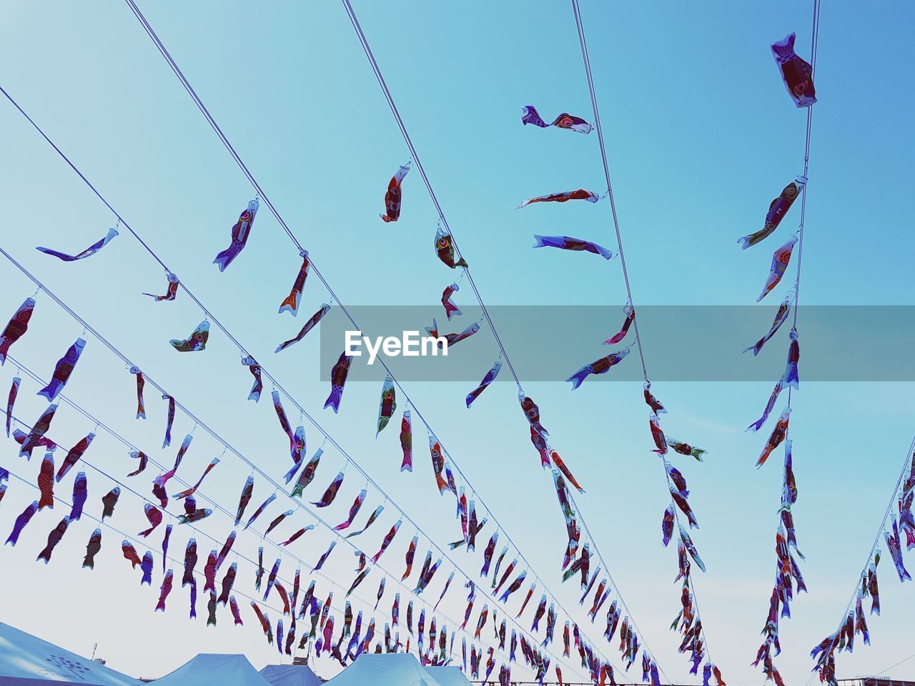 Low angle view of colorful buntings hanging against cloudy sky during sunset