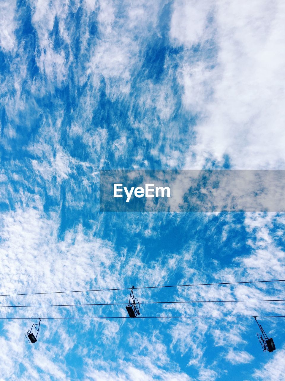 Low angle view of ski lifts against cloudy sky