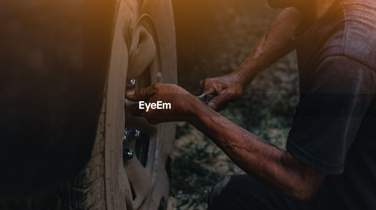 Midsection of man changing car tire