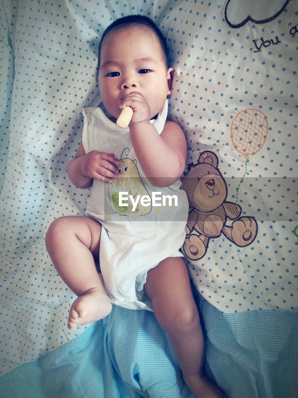 Directly above portrait of baby lying on bed