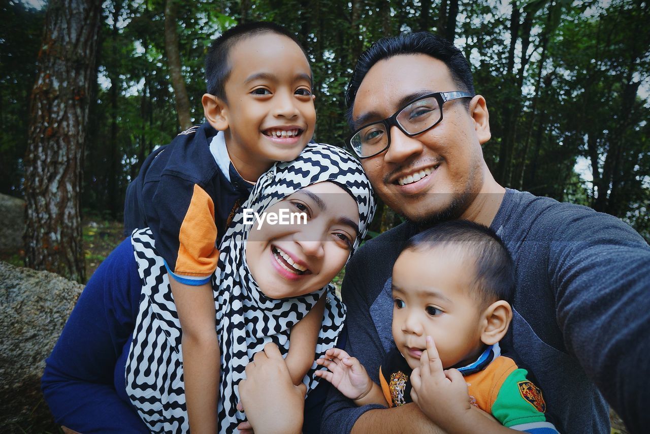 Portrait of happy family with boy against trees