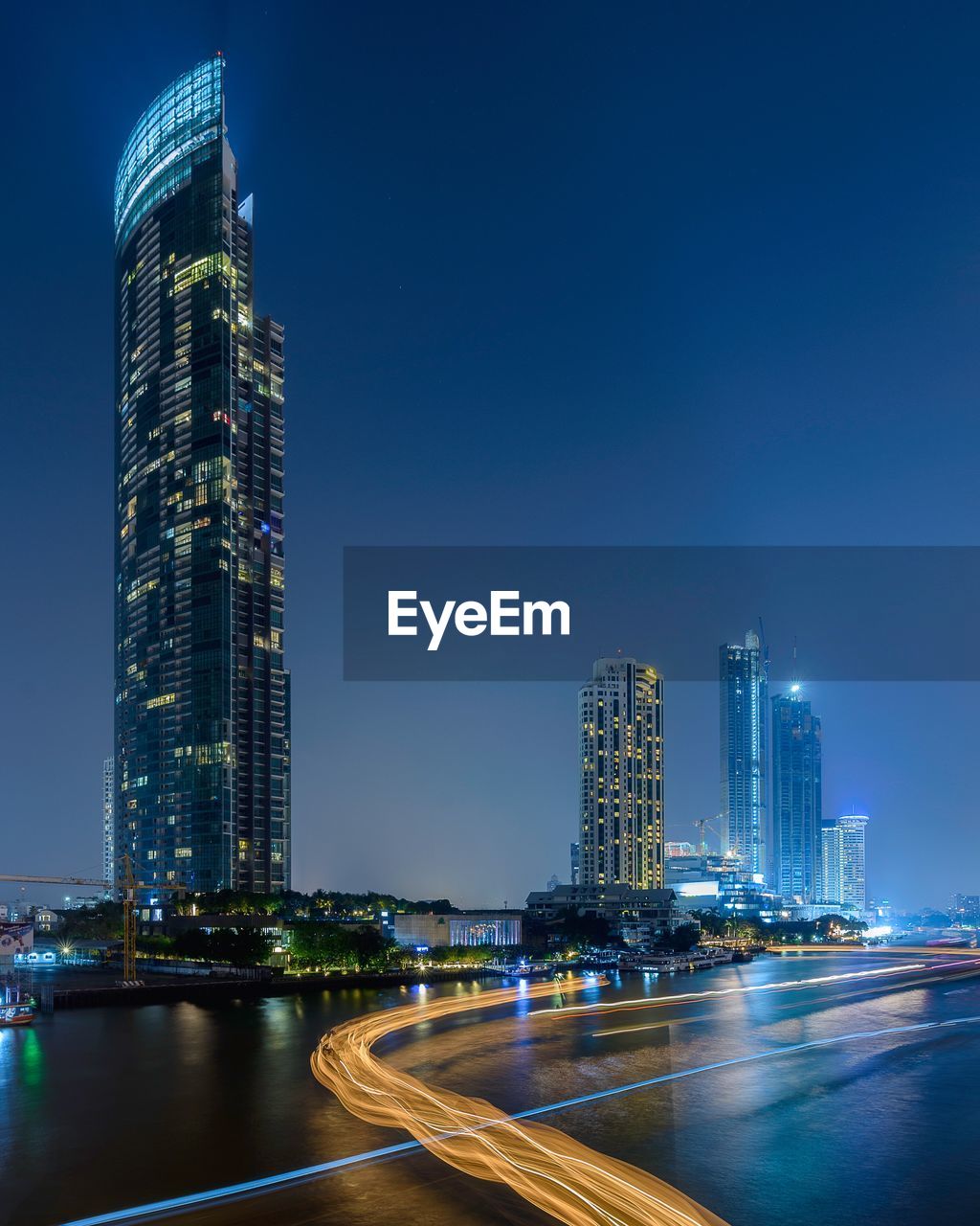 Illuminated modern buildings in city against sky at night