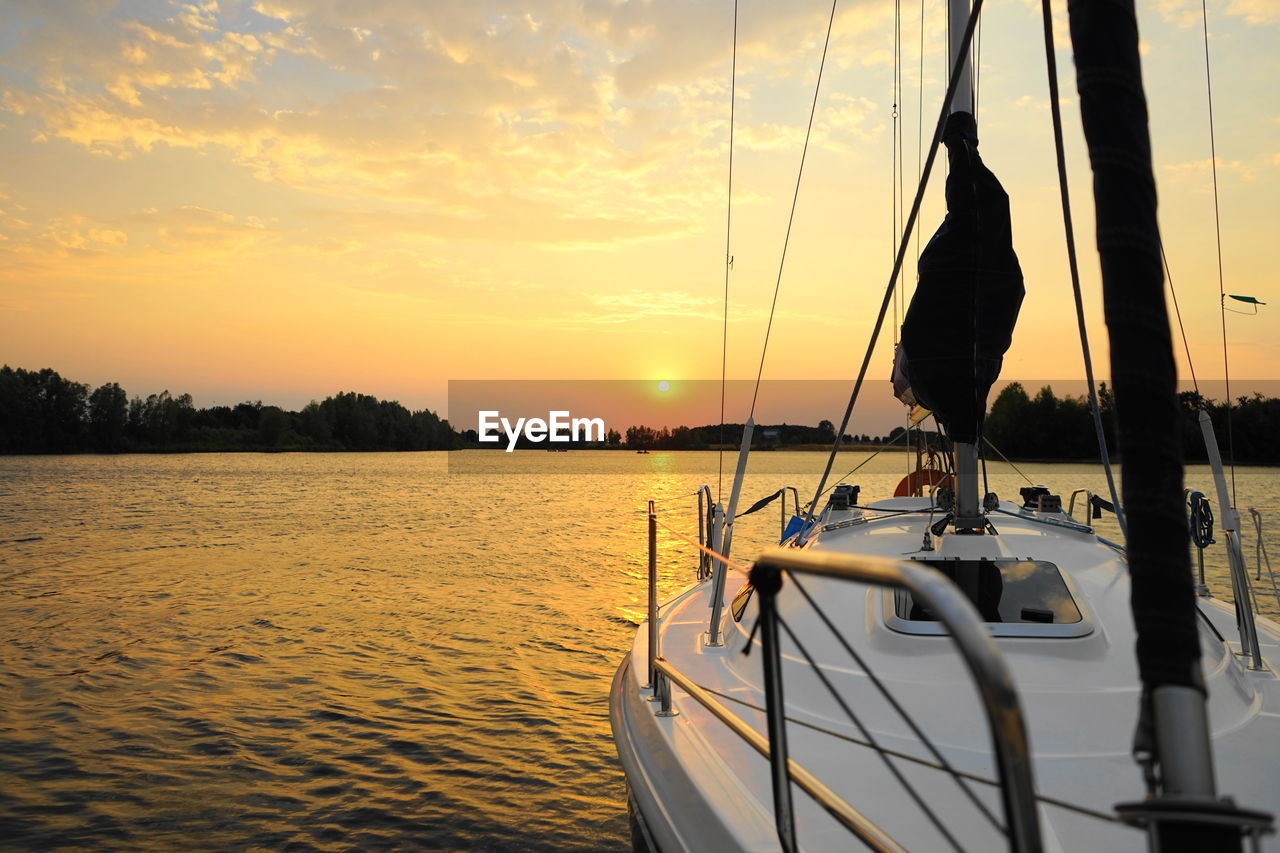 SAILBOATS IN SEA AT SUNSET