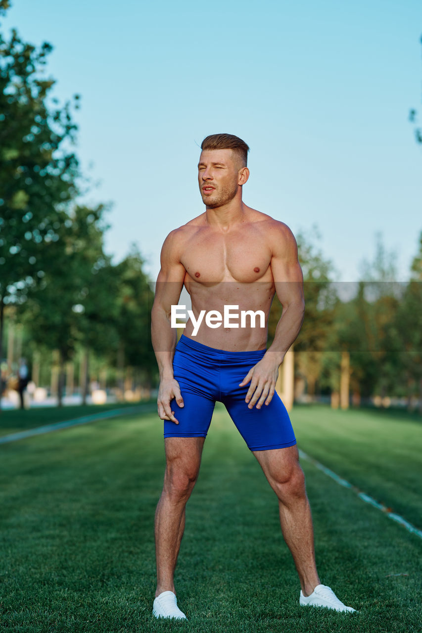 portrait of shirtless man exercising on field