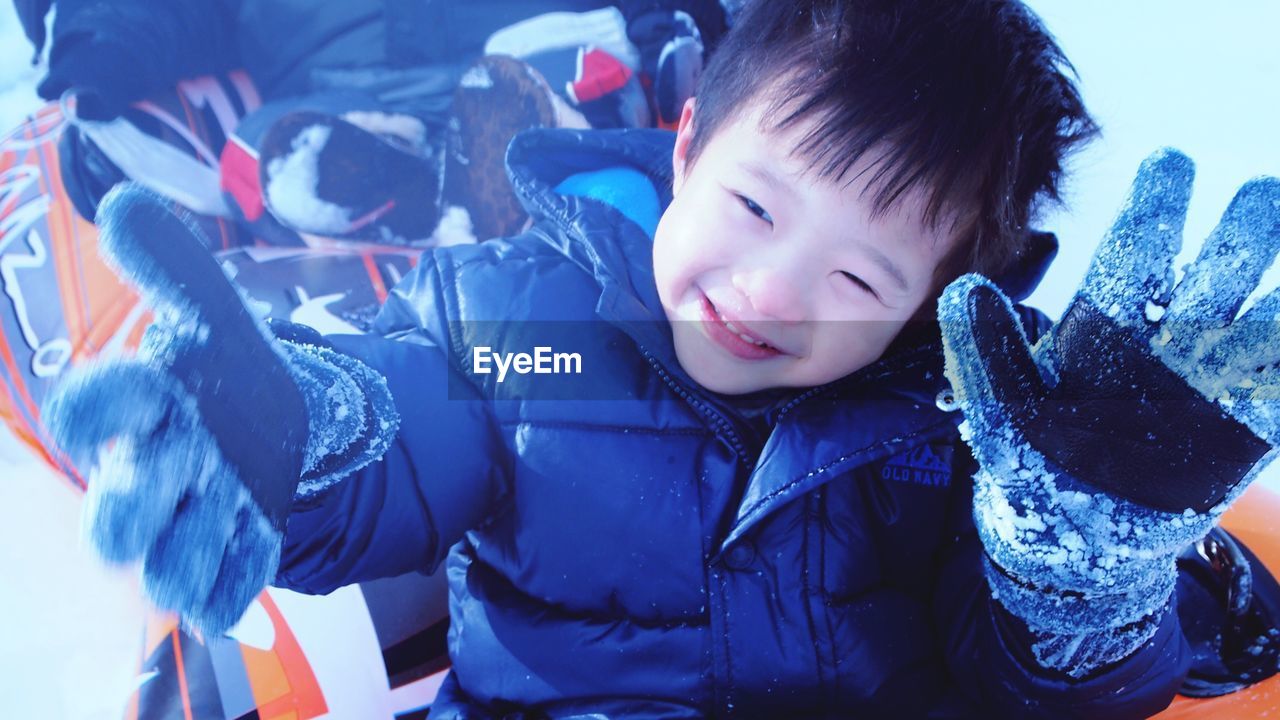 CLOSE-UP OF SMILING BOY WITH SNOW