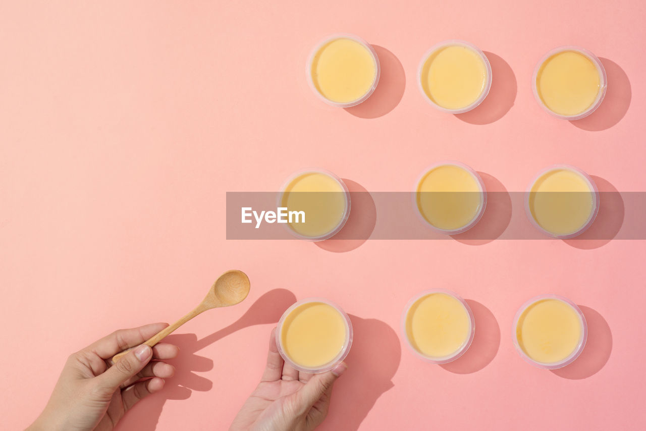 Hand putting creme caramel in minimalist style setup on pink background