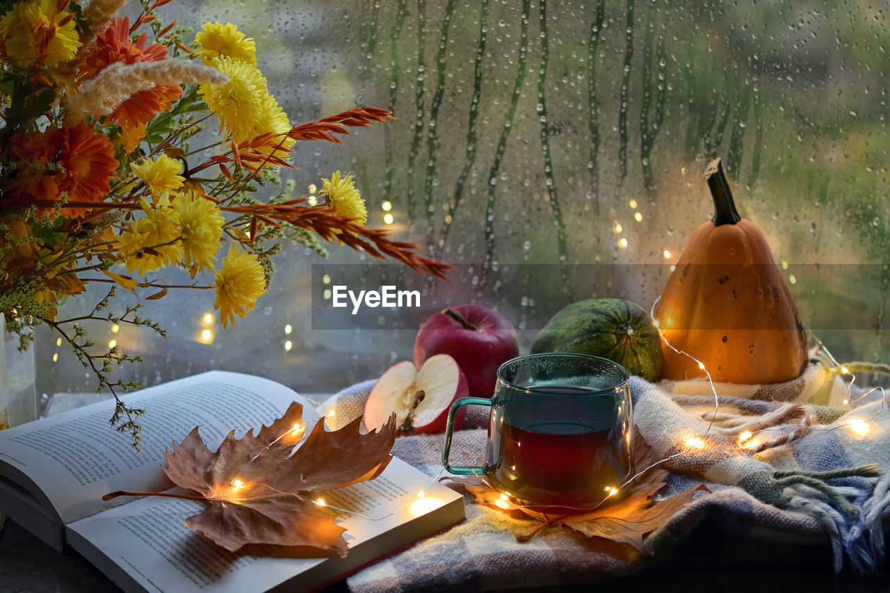 Autumn decor with flowers, open book and cup of tea