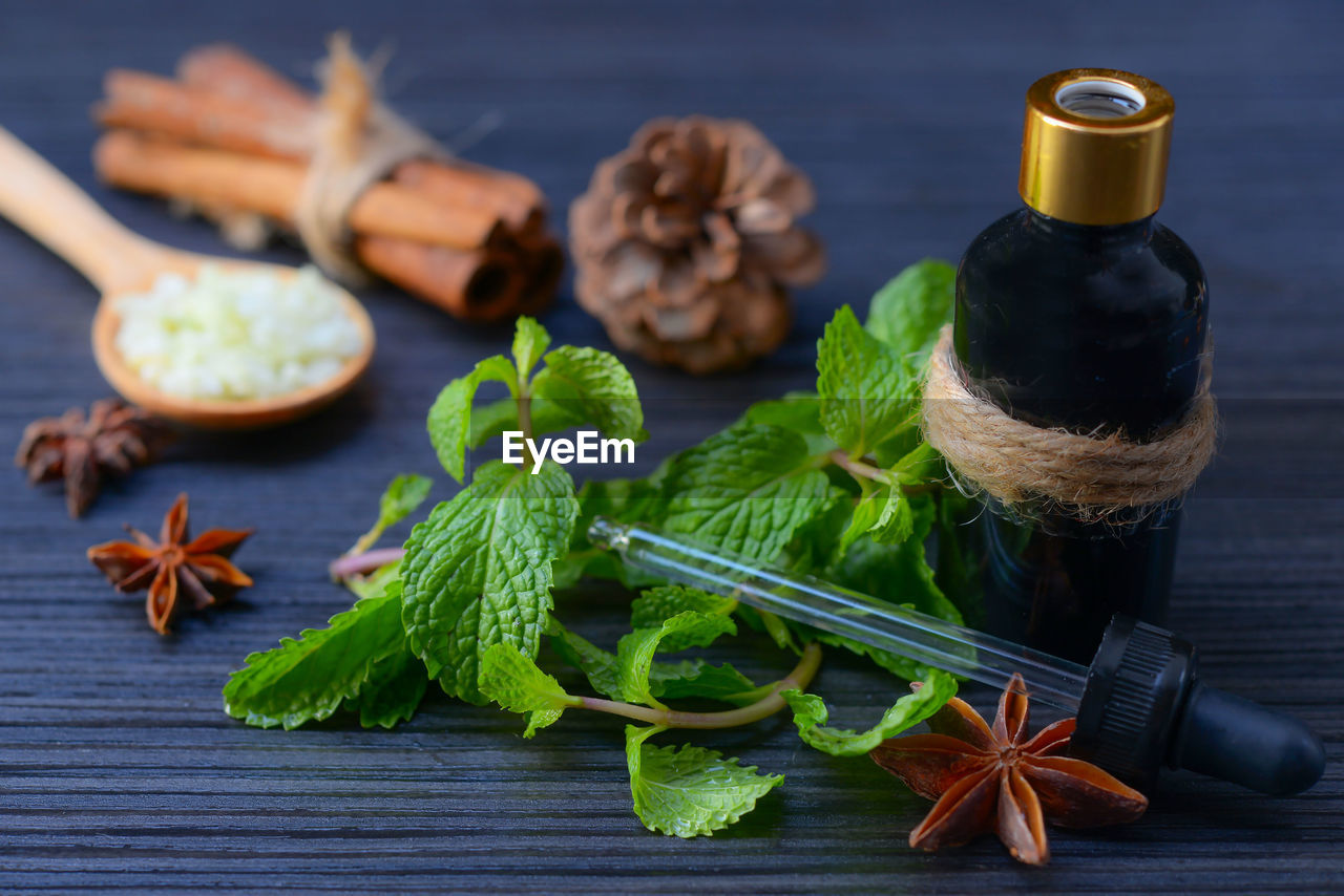 Close-up of mint leaves with bottle and dropper on table