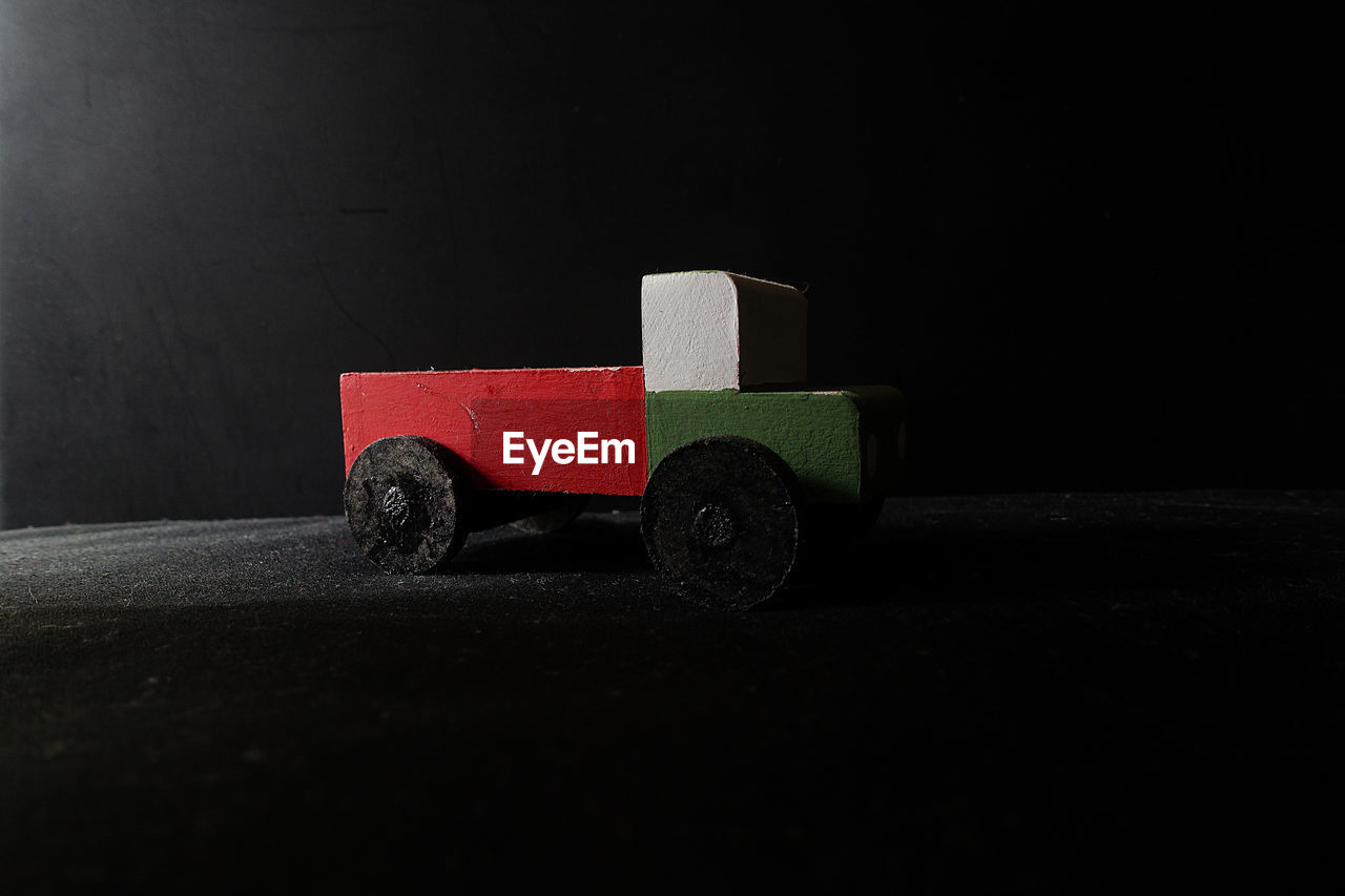 Close-up of wooden truck on table against black background