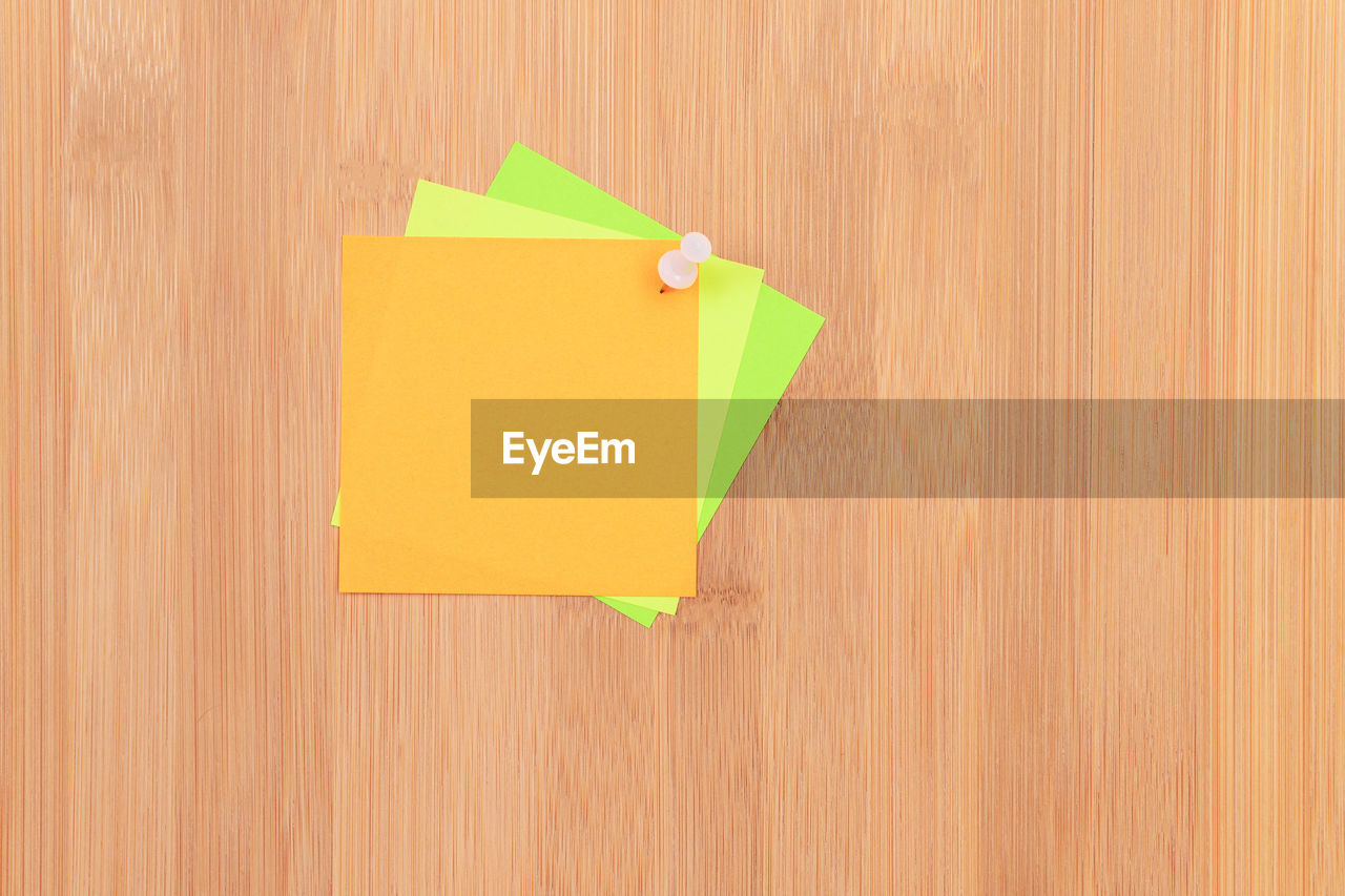 DIRECTLY ABOVE SHOT OF YELLOW PAPER ON WOODEN SURFACE