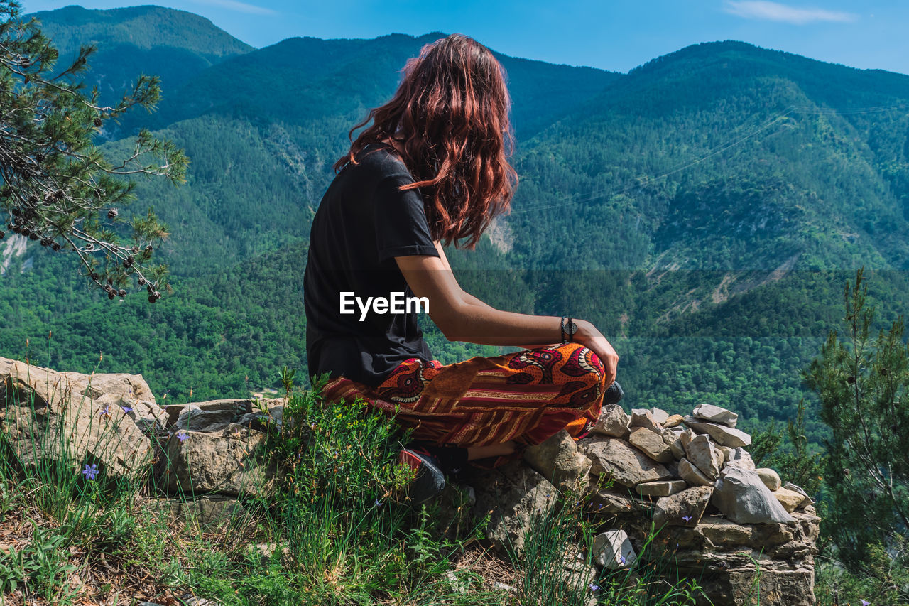 WOMAN SITTING ON MOUNTAIN