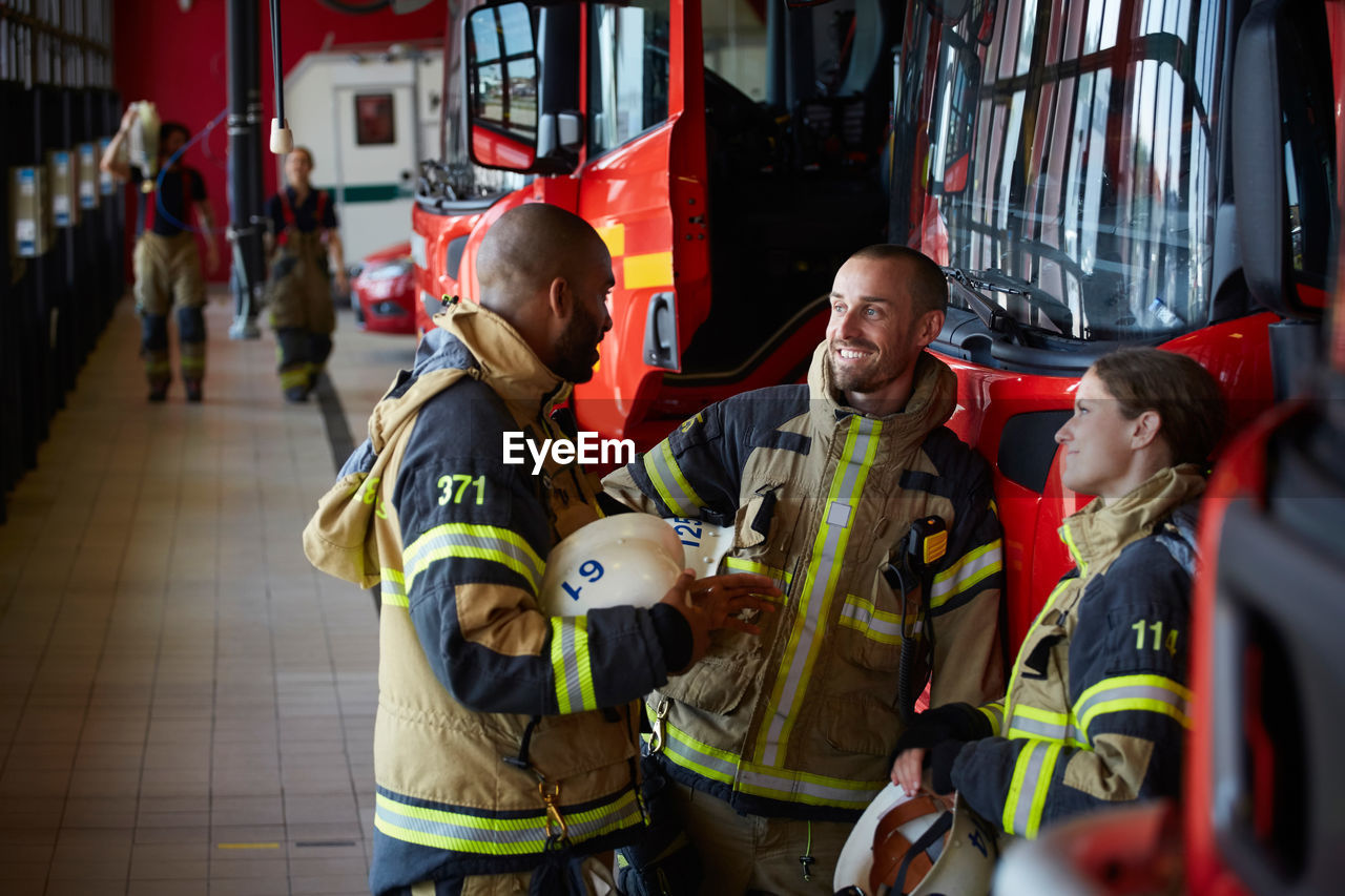 Firefighters in uniform talking while standing at fire station