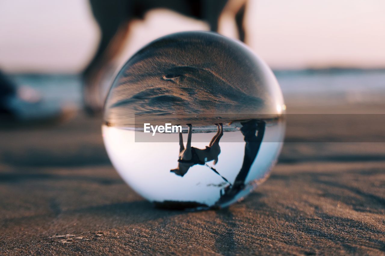CLOSE-UP OF CRYSTAL BALL ON SHORE