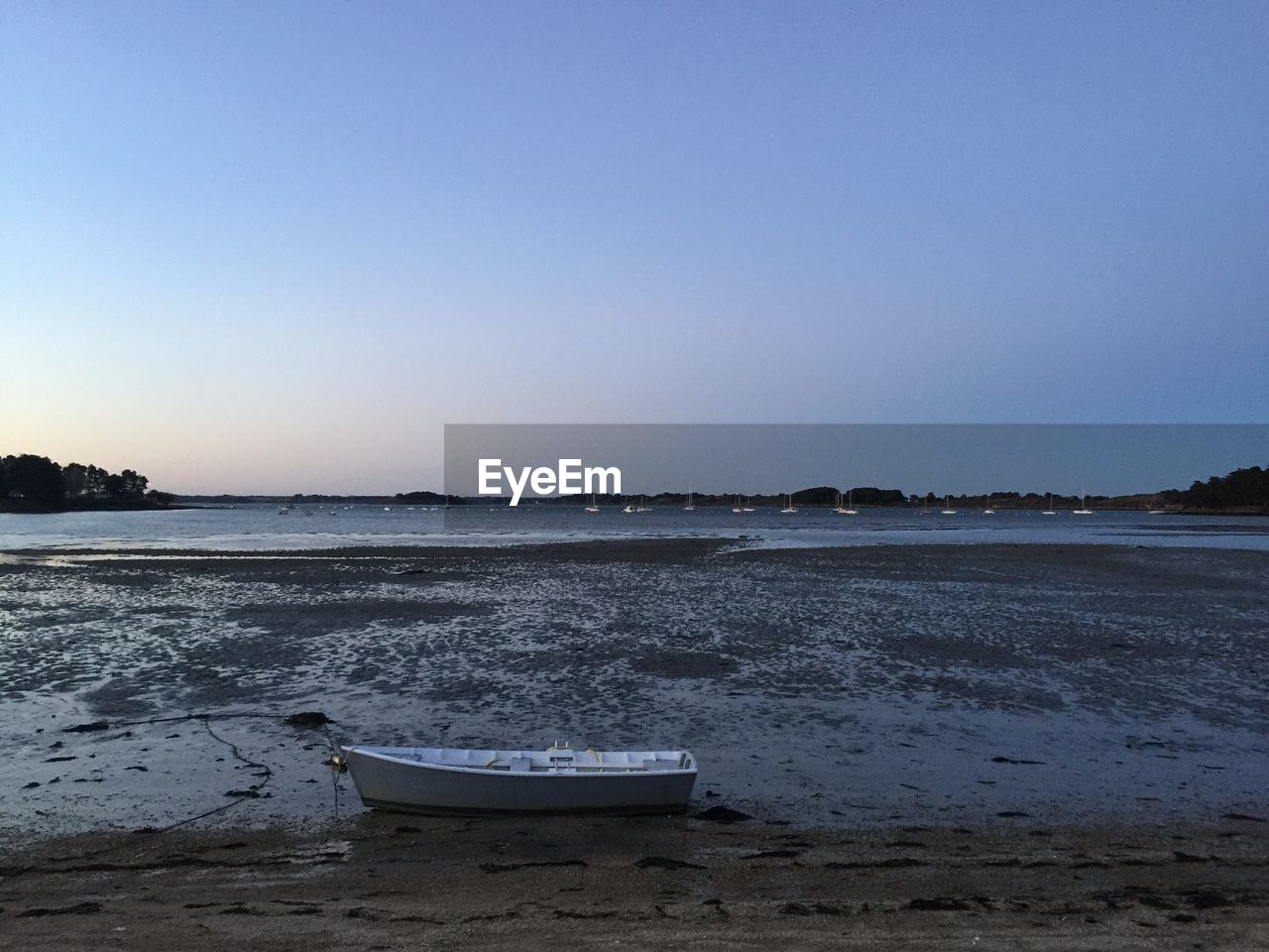 Scenic view of boat on calm seashore against clear sky