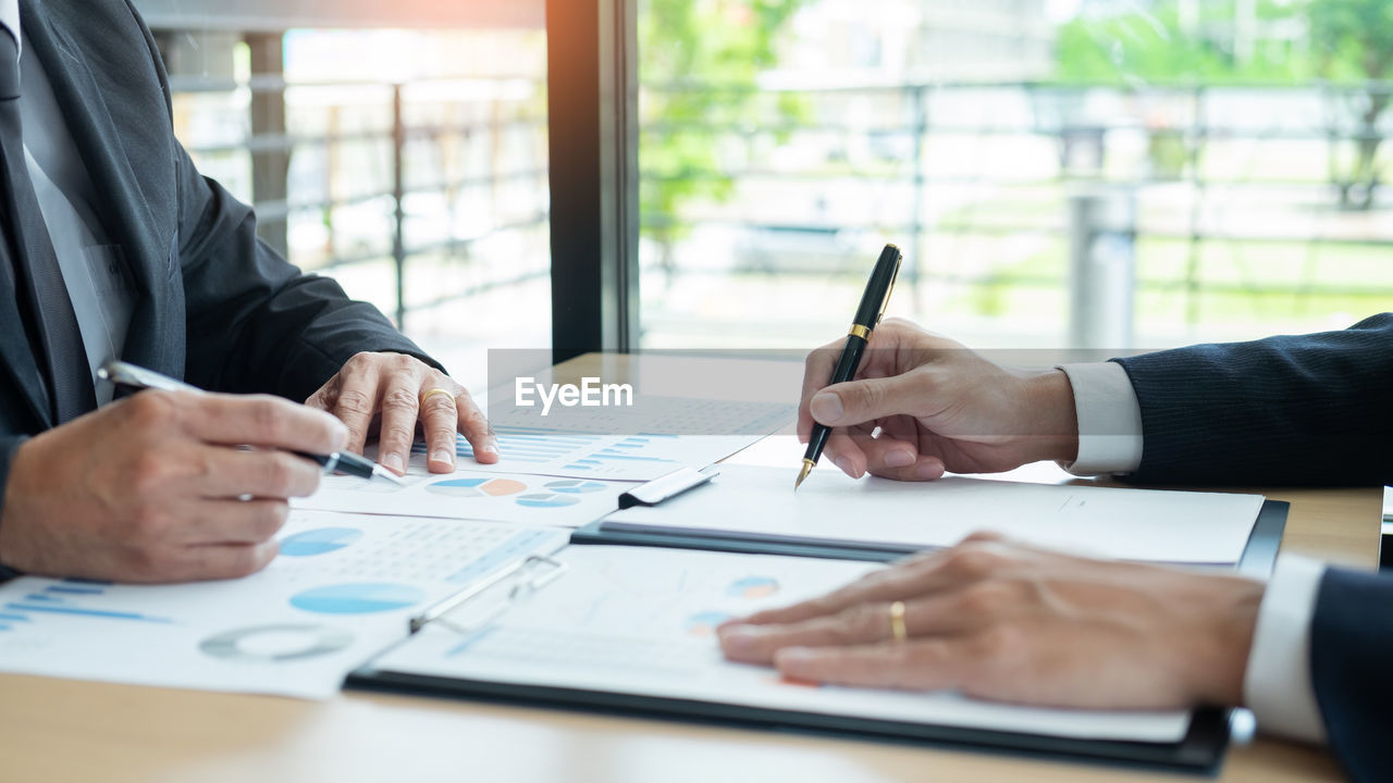 Cropped image of businessmen working on desk in office