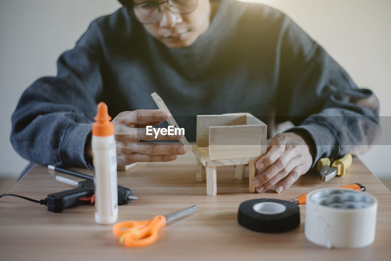 Focus on young man's hand assembling wood, diy wood work, close up.
