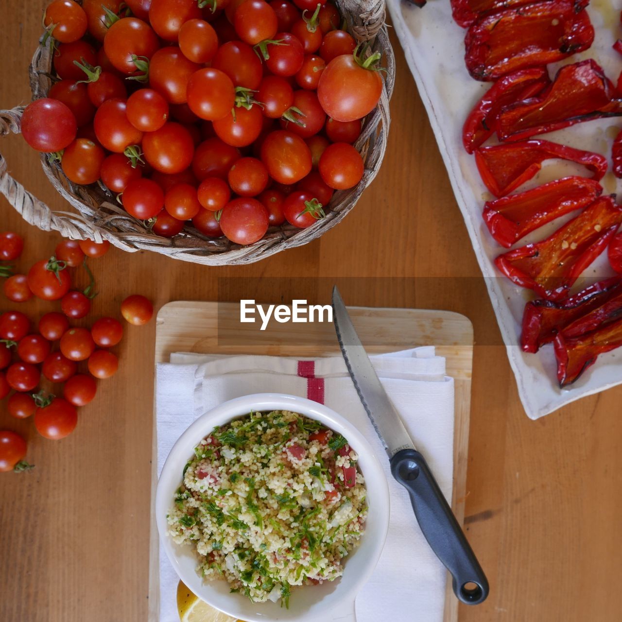 Directly above shot of tabbouleh with knife besides tomatoes and bell peppers