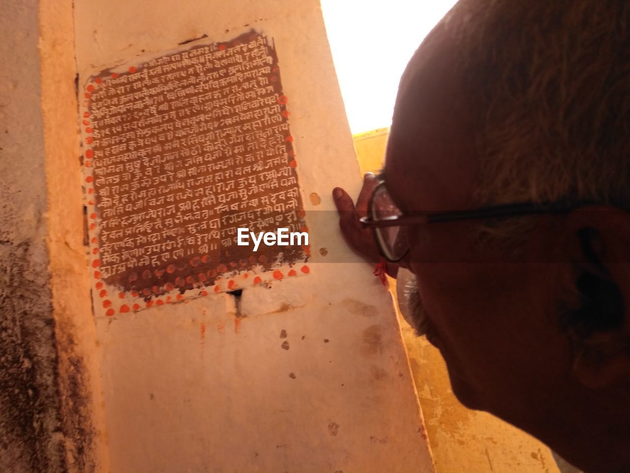 CLOSE-UP OF MAN HAND WITH EYEGLASSES ON WALL