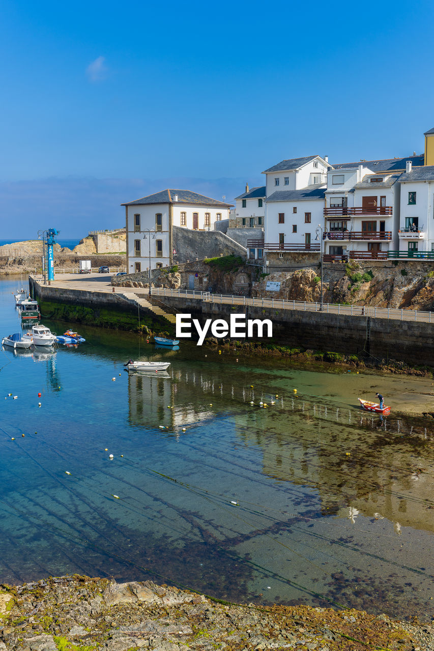 Buildings by river against clear sky