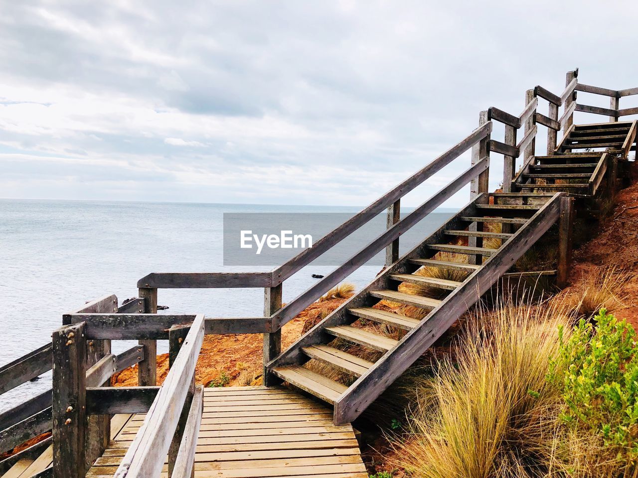 Staircase leading towards sea against sky