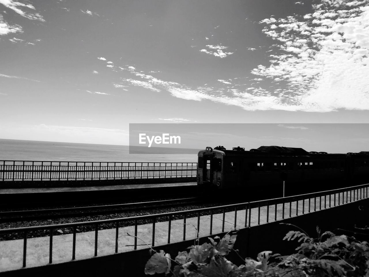 TRAIN ON BRIDGE AGAINST SKY AT RAILROAD STATION