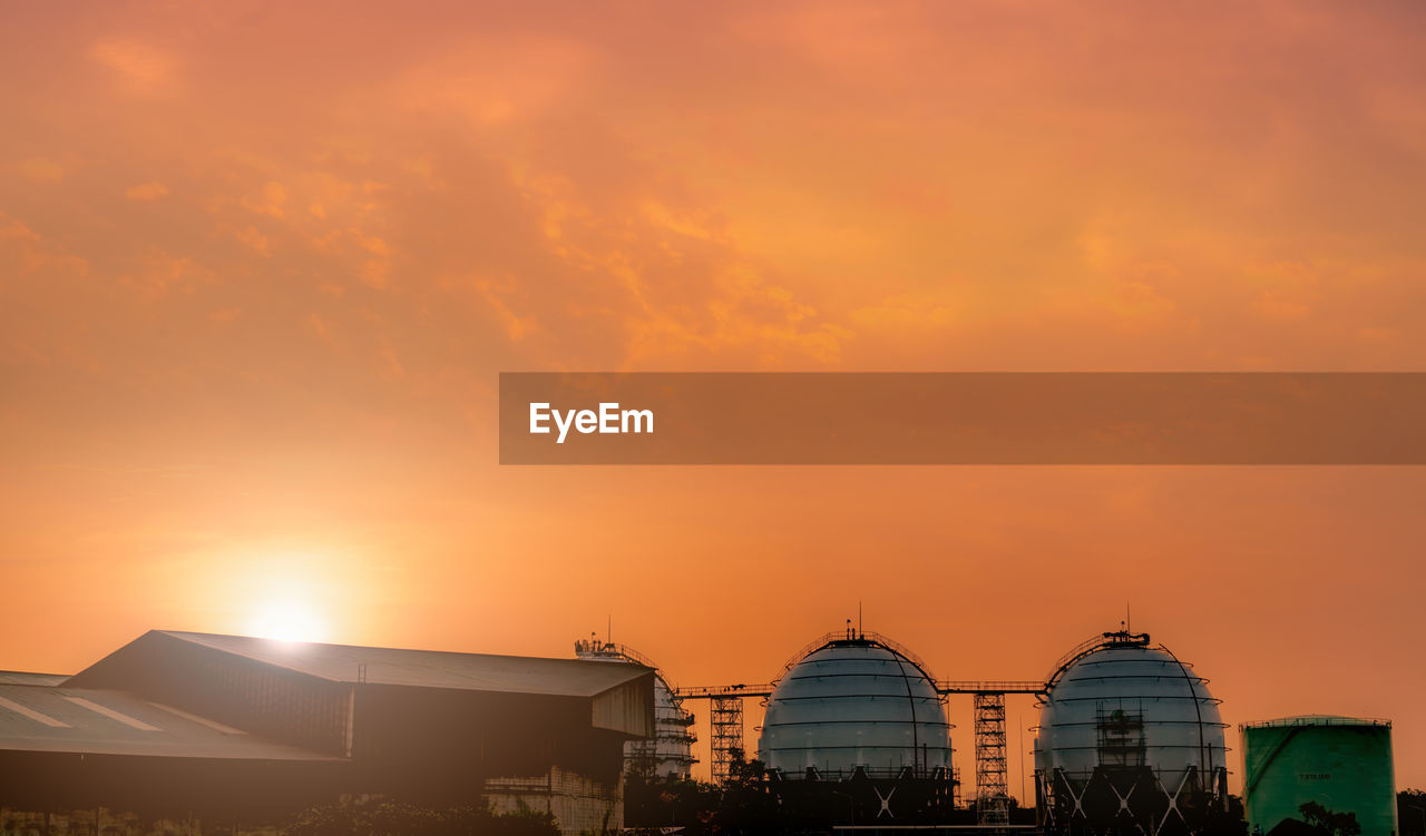 Industrial gas storage tank. lng or liquefied natural gas storage tank. red and orange sunset sky.