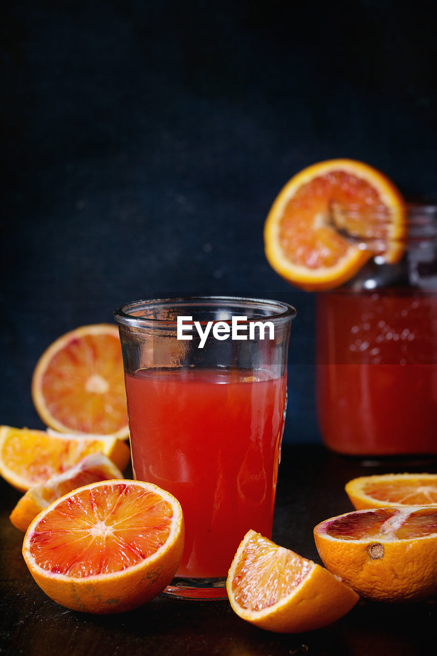 Close-up of orange fruit with juice on table against black background