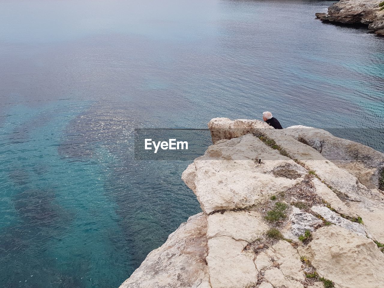 Rear view of man by sea on rock