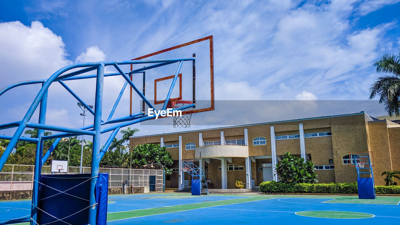 Low angle view of basketball by building against sky
