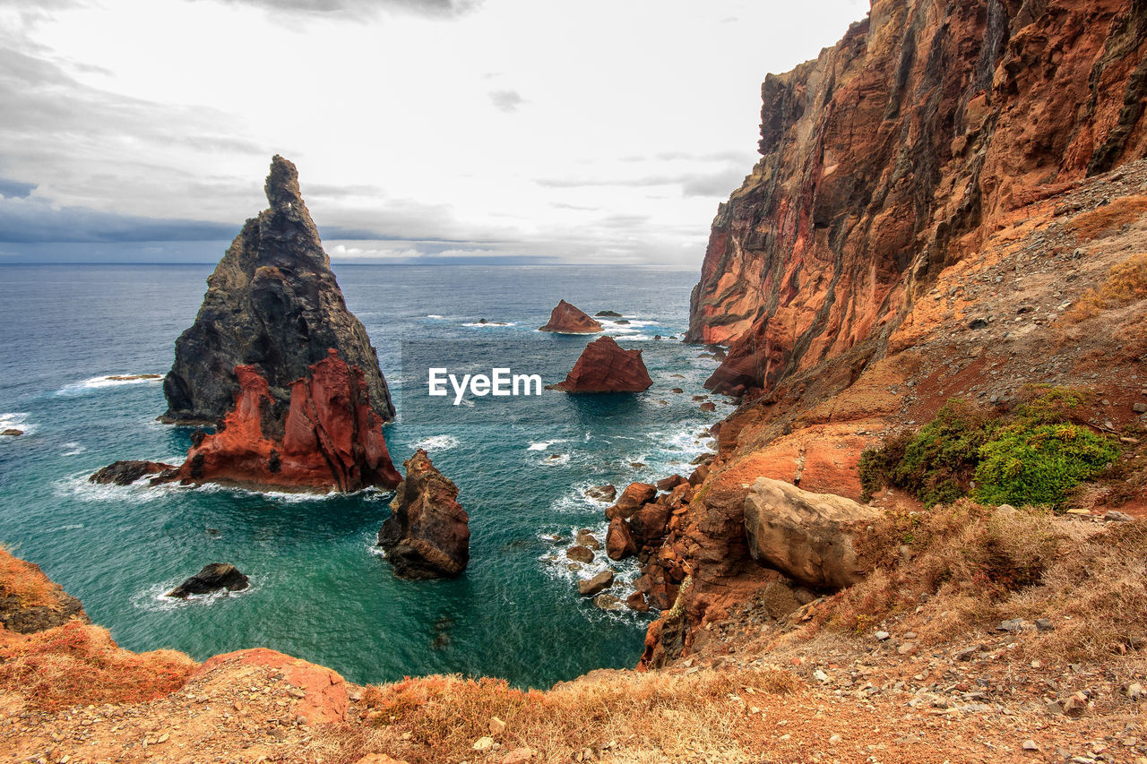 Scenic view of sea and rock formations against cloudy sky