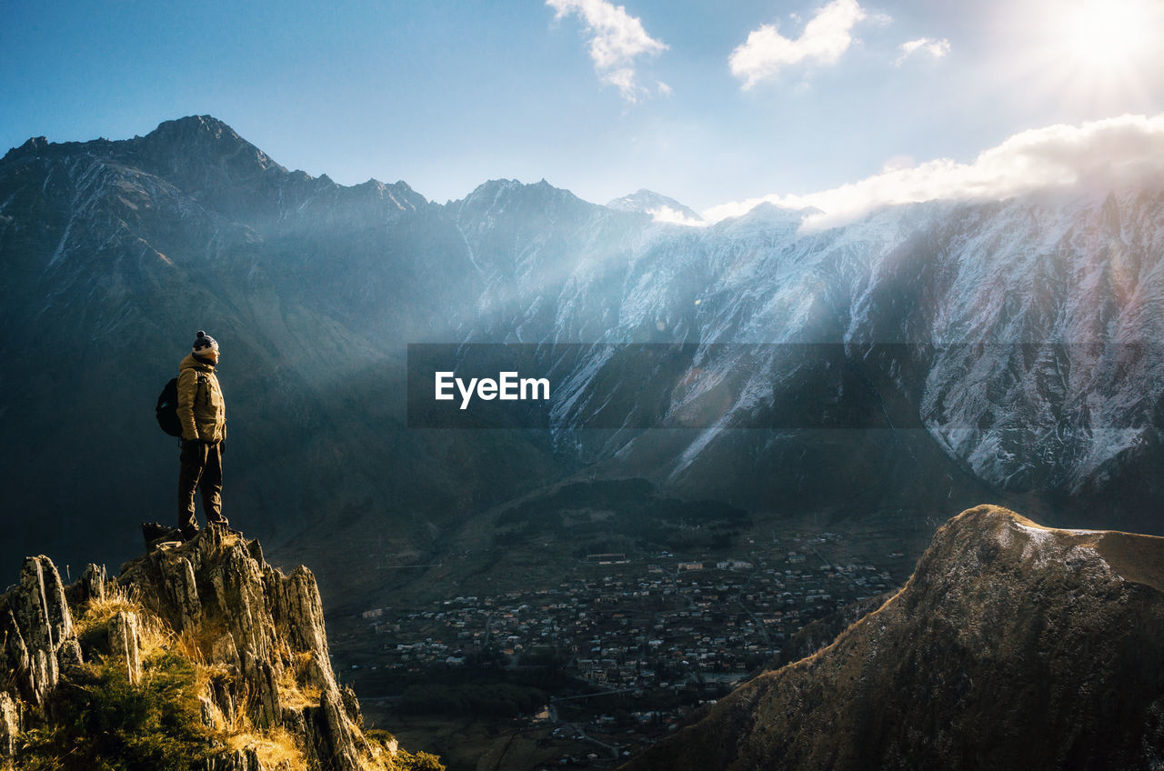 Man looking at mountain ranges against sky during winter