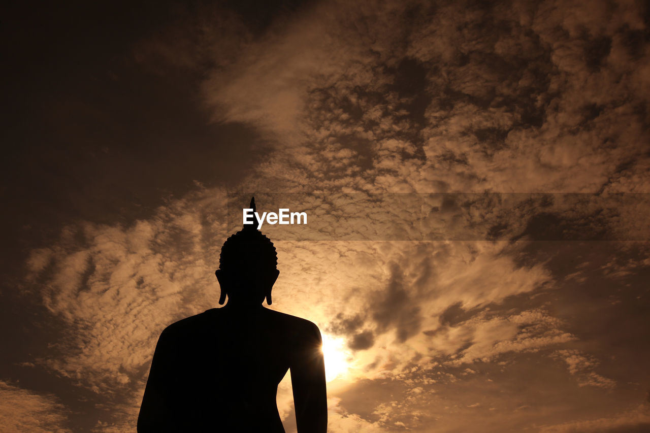Low angle view of silhouette buddha statue against sky during sunset