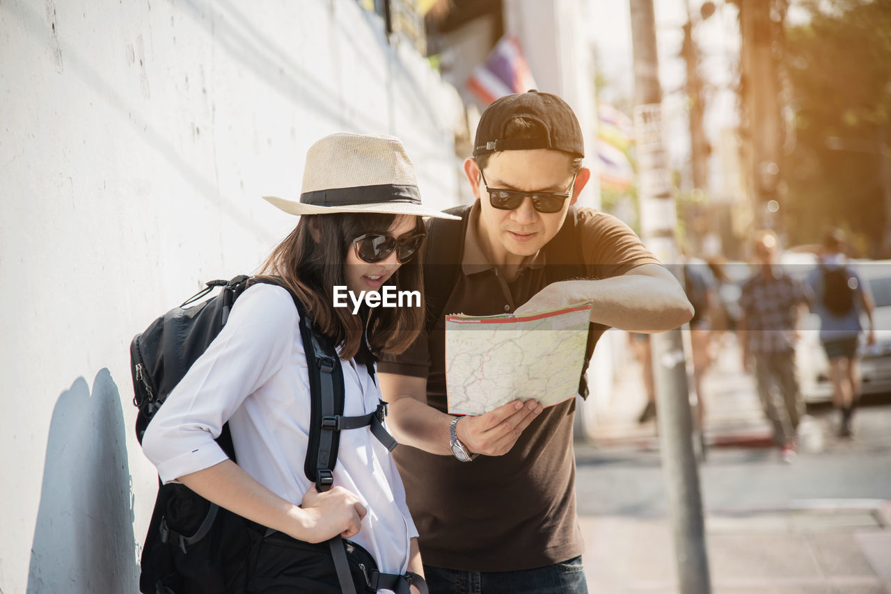 Man discussing map with woman while standing in city