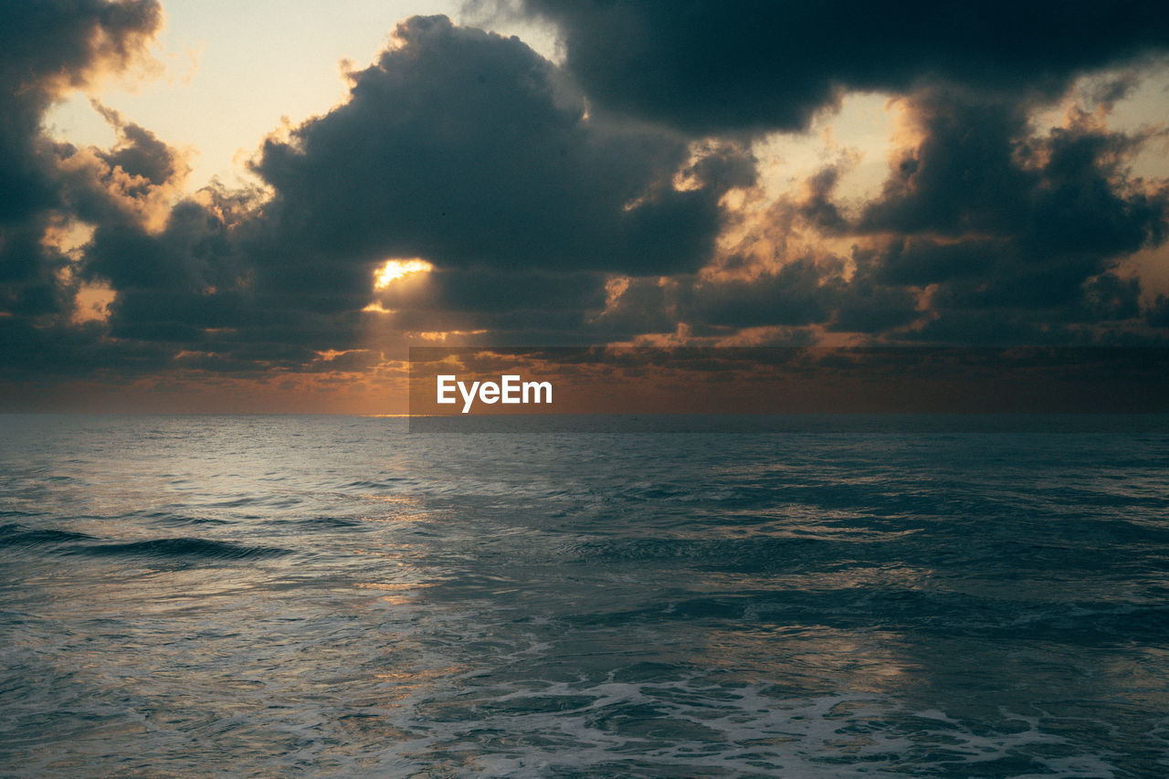 scenic view of sea against cloudy sky during sunset