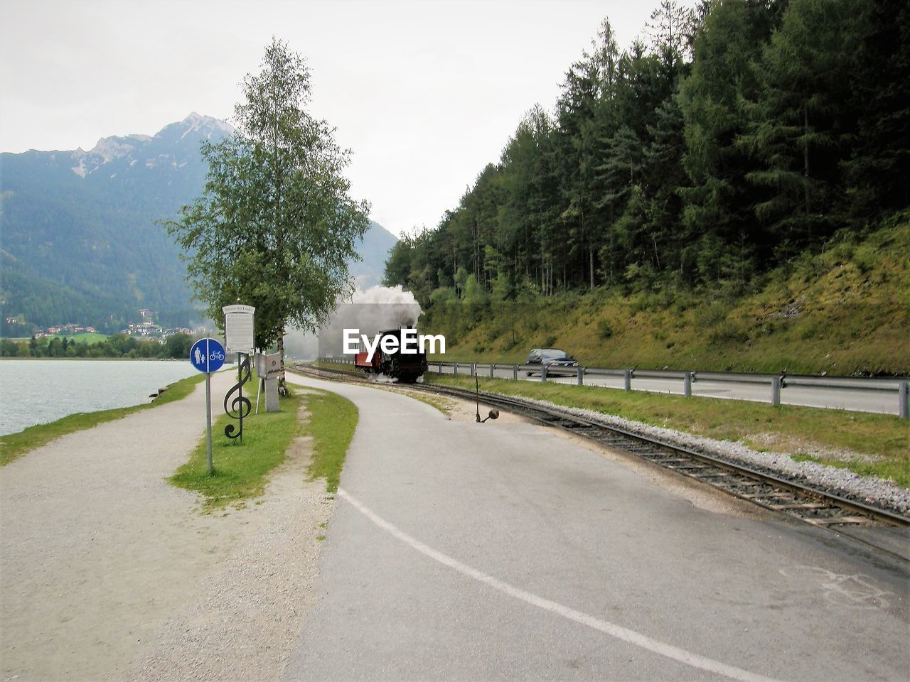 PEOPLE ON ROAD AGAINST TREES AND MOUNTAIN