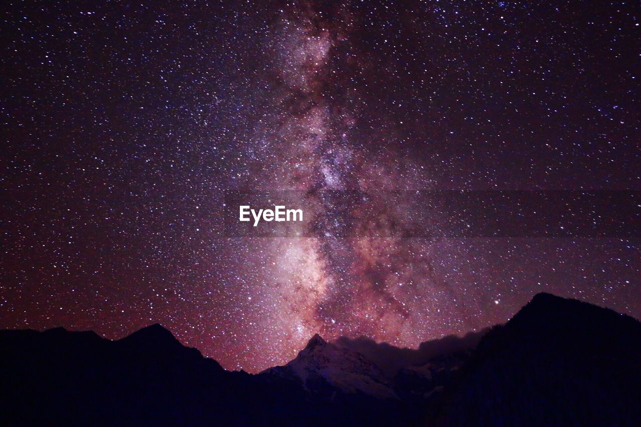 Low angle view of silhouette mountain against star field