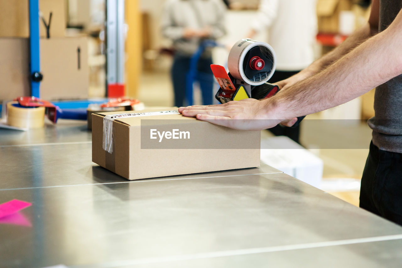 Midsection of man packing box in distribution warehouse