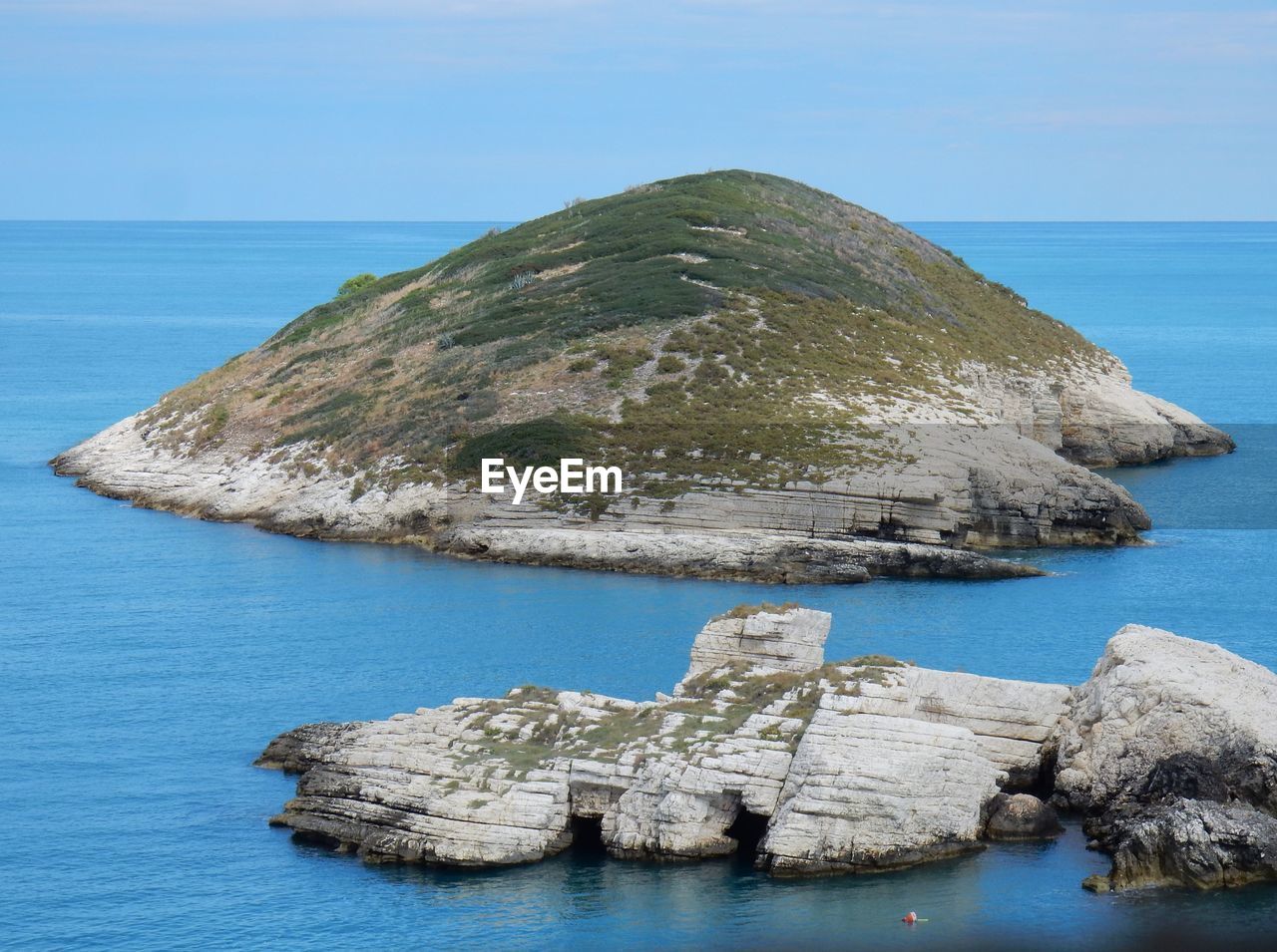 Scenic view of rock formation in sea against clear sky