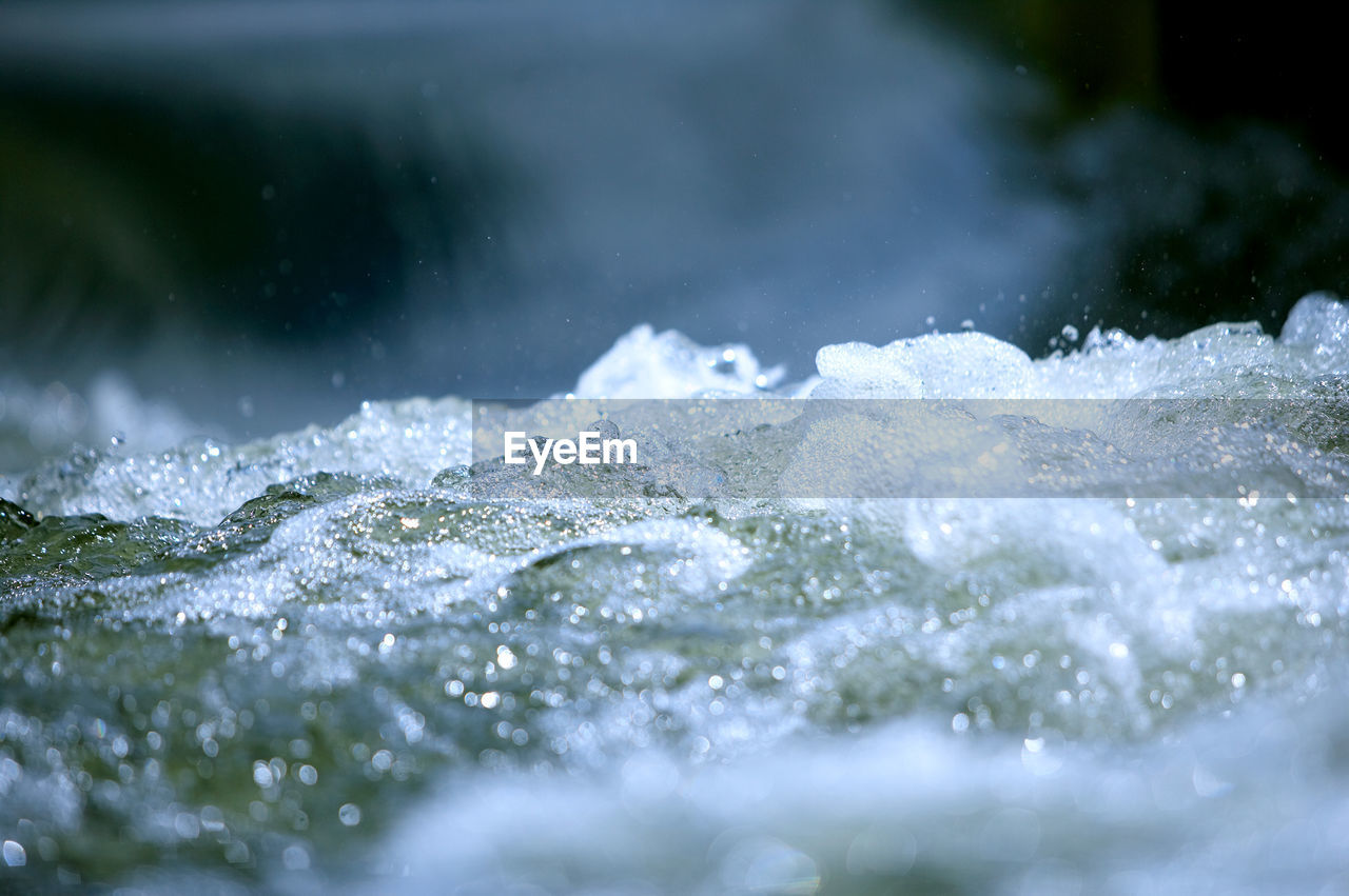 CLOSE-UP OF WATER SPLASHING AGAINST WATERFALL