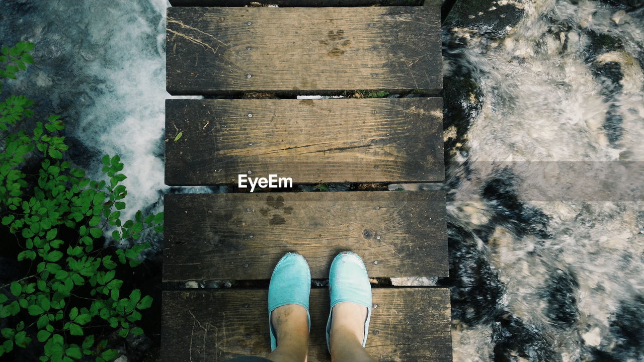 Low section of person standing on narrow bridge