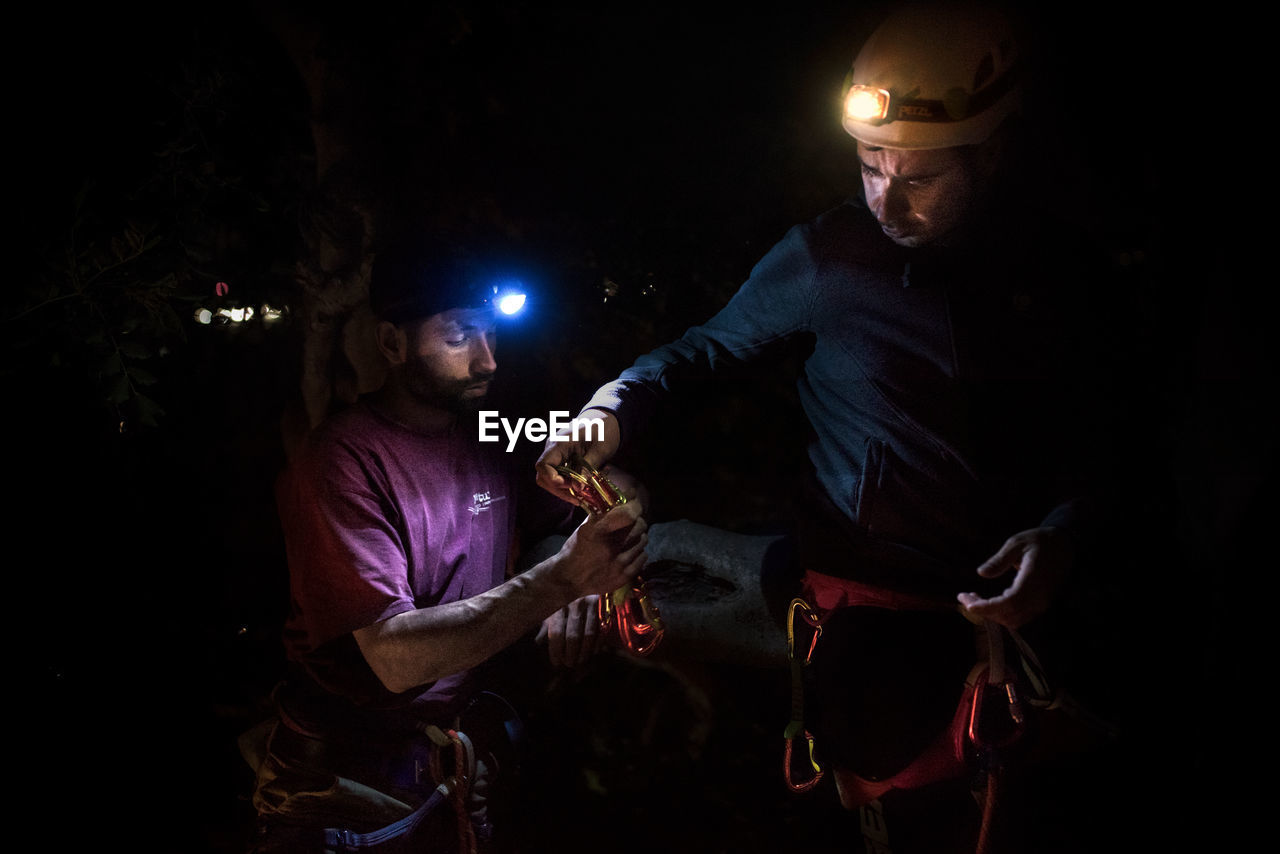 Male friends climbing mountain at night