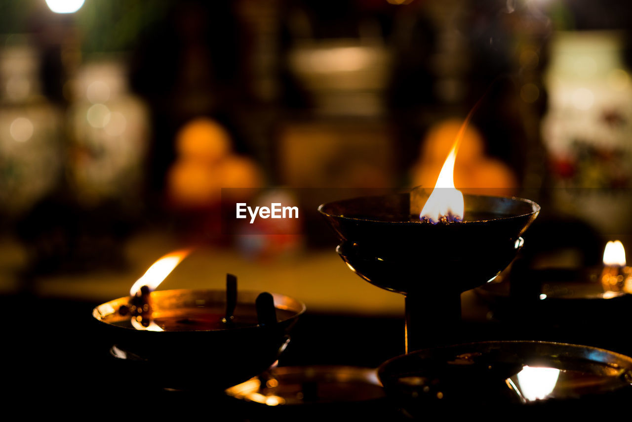 CLOSE-UP OF LIT CANDLE IN TEMPLE